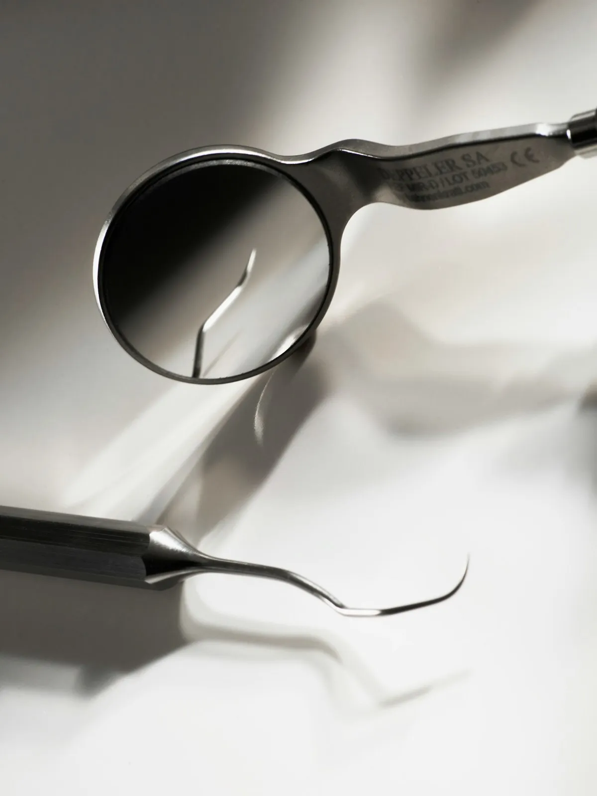 A dental mirror and explorer on a clean white surface